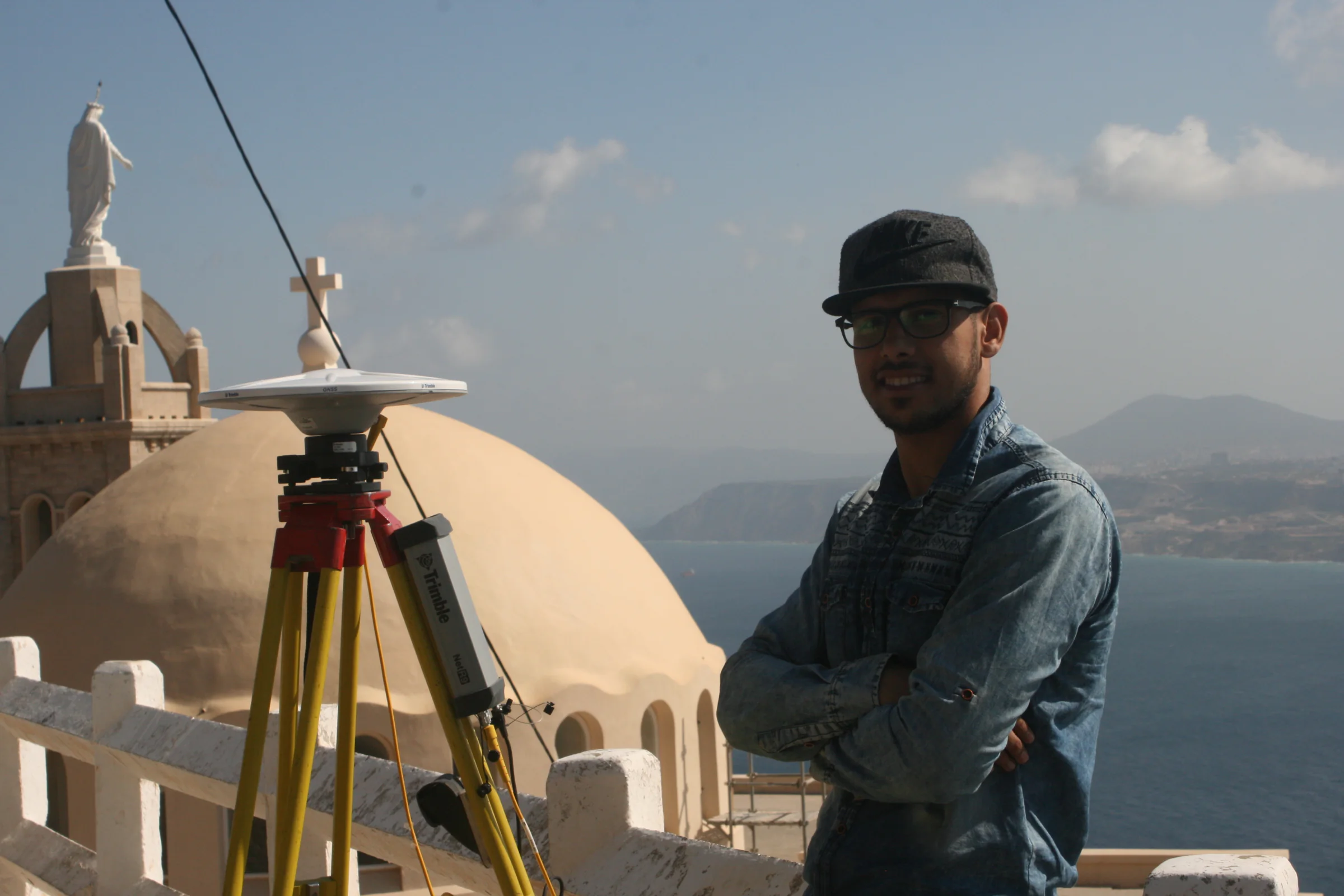 Géomètre et récepteur GNSS devant la chapelle et la statue de Santa Cruz à Oran